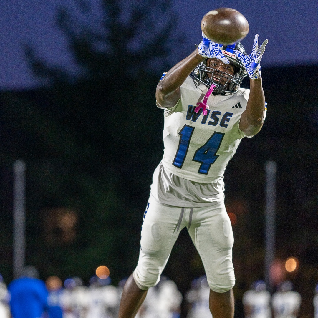 Mikael James, student-athlete, going up for a catch during a night game